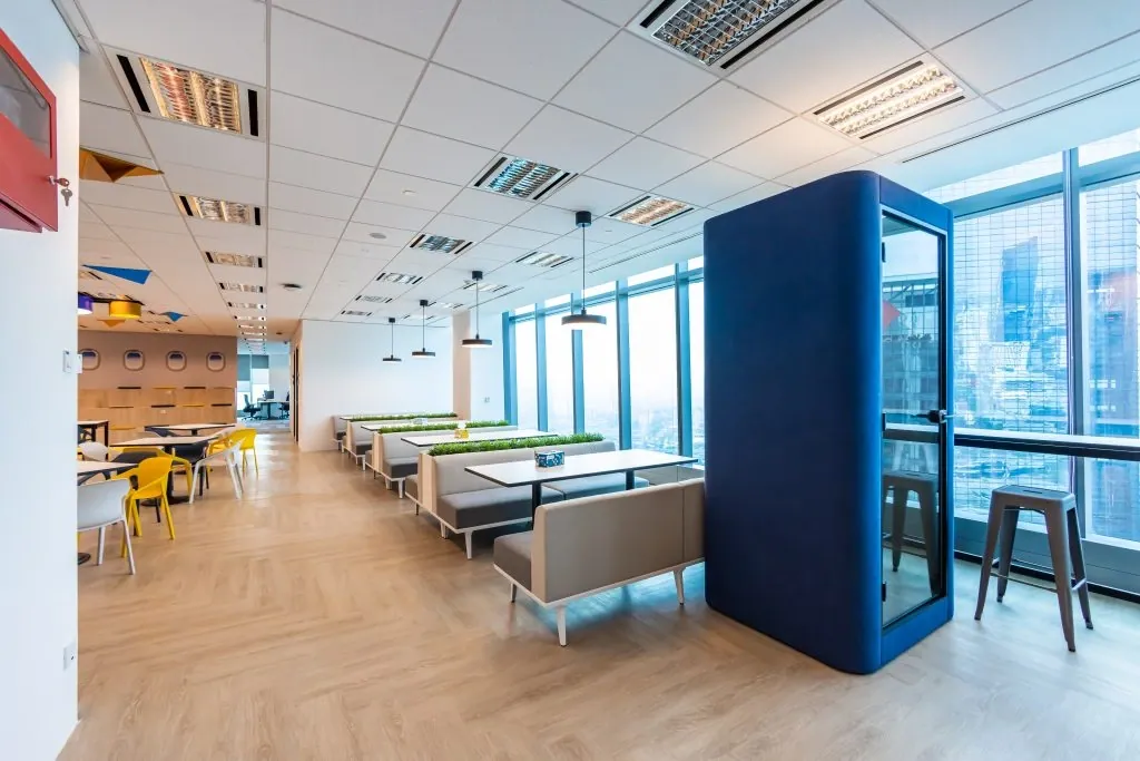 Office pantry with bench seating, planter dividers and a phone booth by the windows