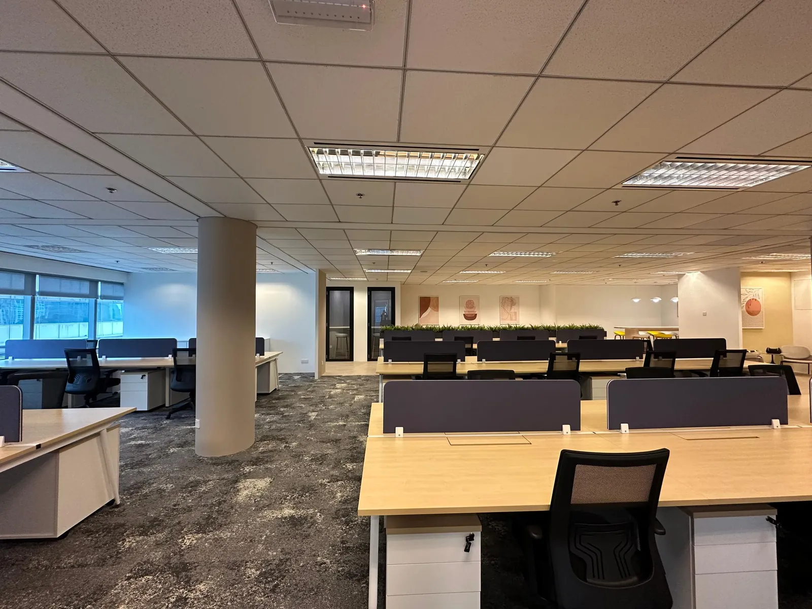 Open-plan office floor with rows of workstations by the window