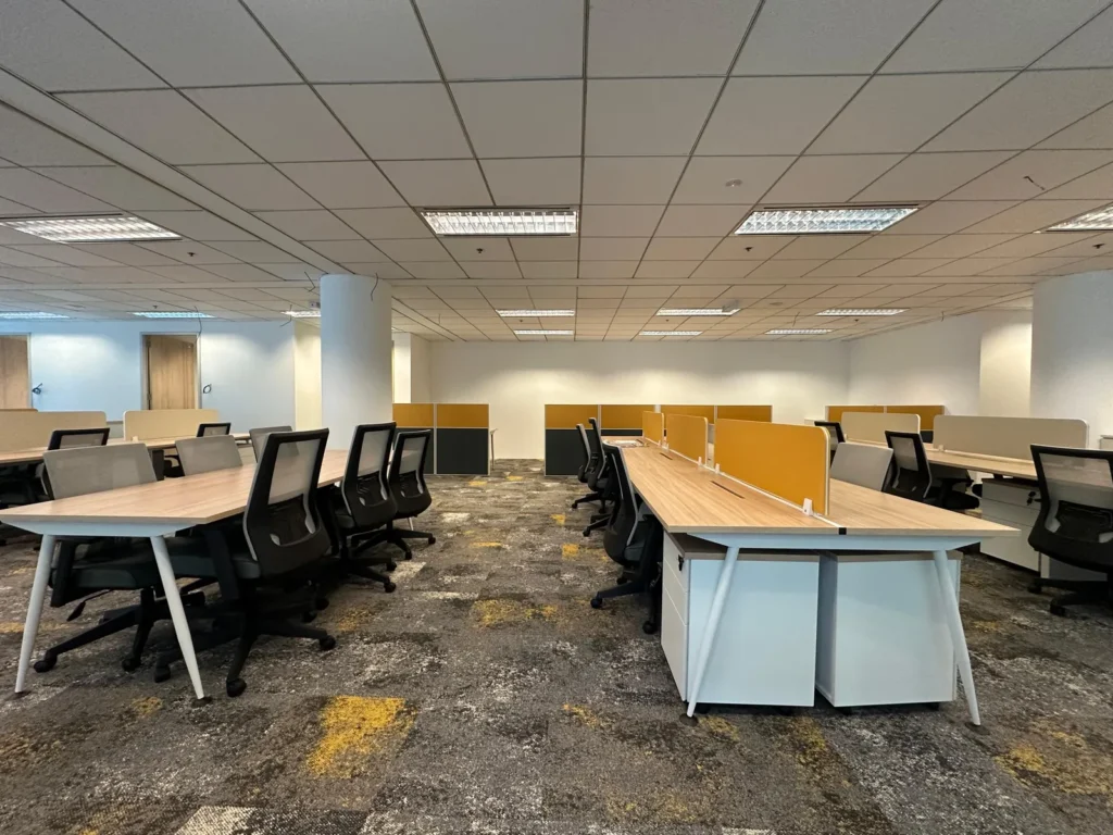 Open-plan office floor with rows of workstations and task chairs
